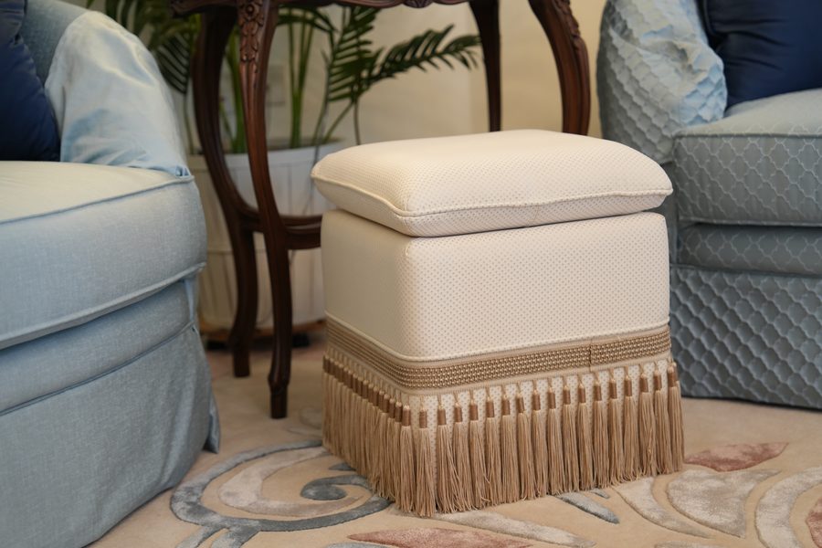 Fringed ottoman between blue sofas