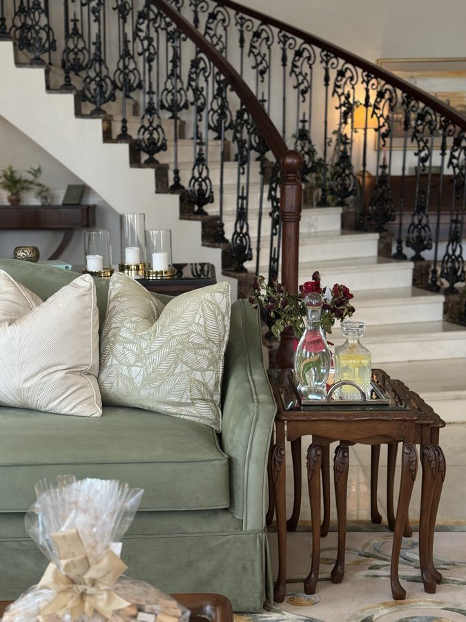 Sage sofa beneath an ornate staircase