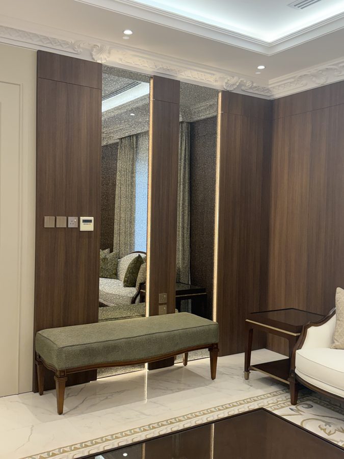Upholstered bench by a walnut-panelled wall
