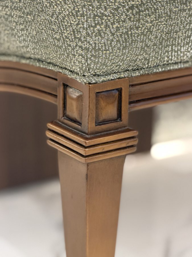 Carved leg beneath sage upholstery