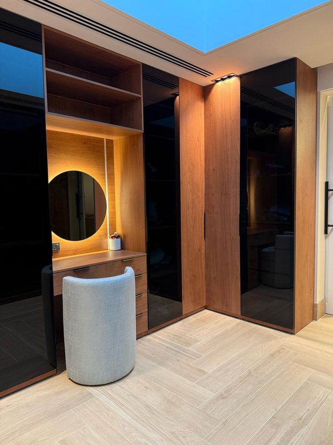 Dressing corner with a backlit round mirror and walnut wardrobes