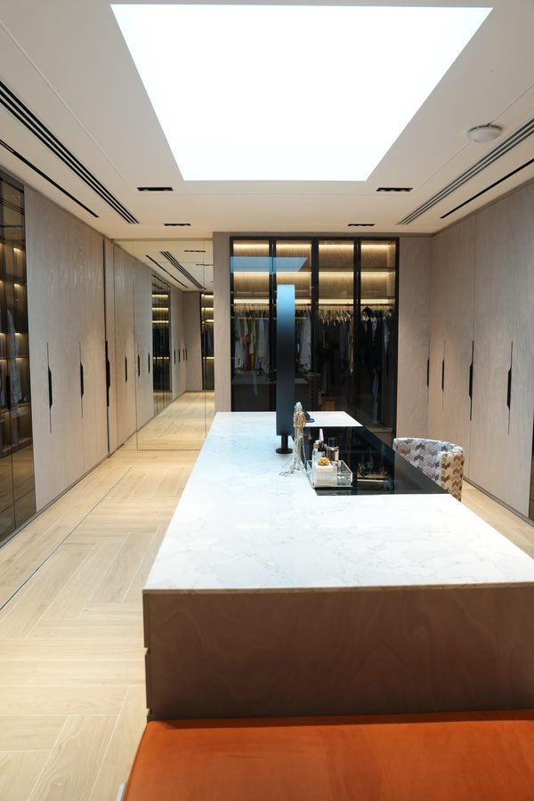 Long dressing room with a marble island beneath a skylight