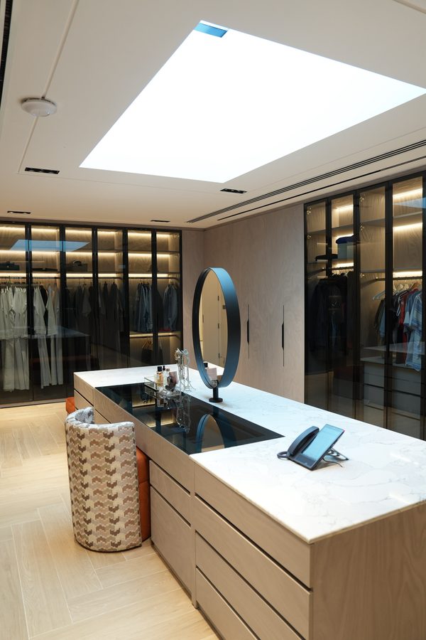 Dressing-room island with a round mirror and glass-fronted wardrobes