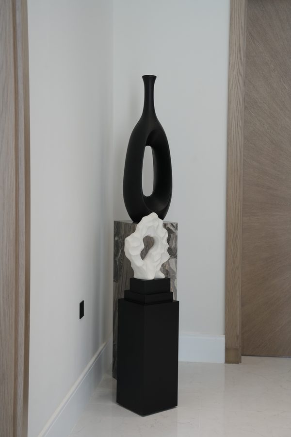 Black sculpture on a plinth in a niche