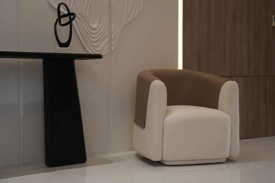 Console and cream armchair beside a sculpted wall